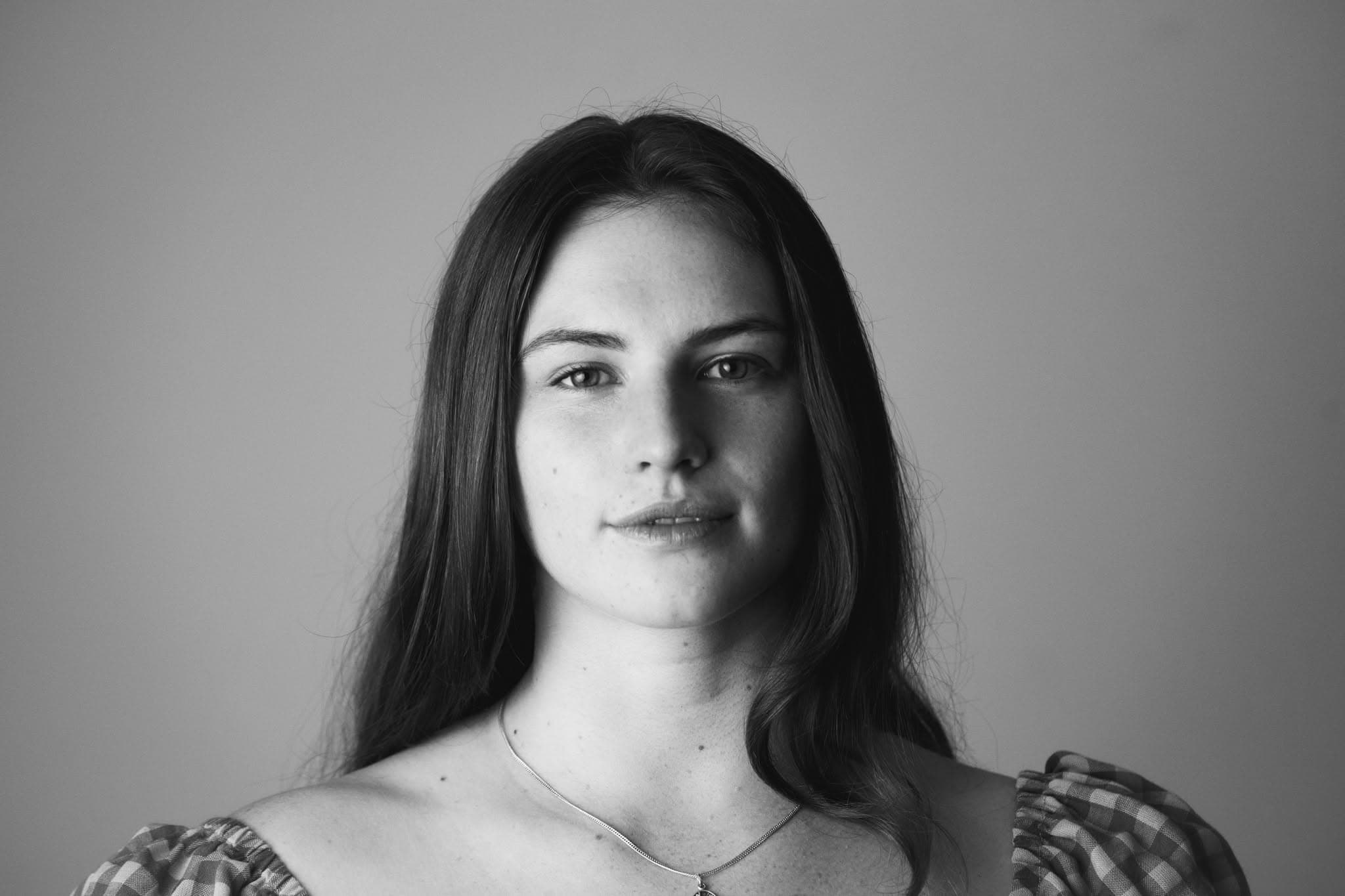 Black and white portrait of a young woman with long hair and a direct gaze.